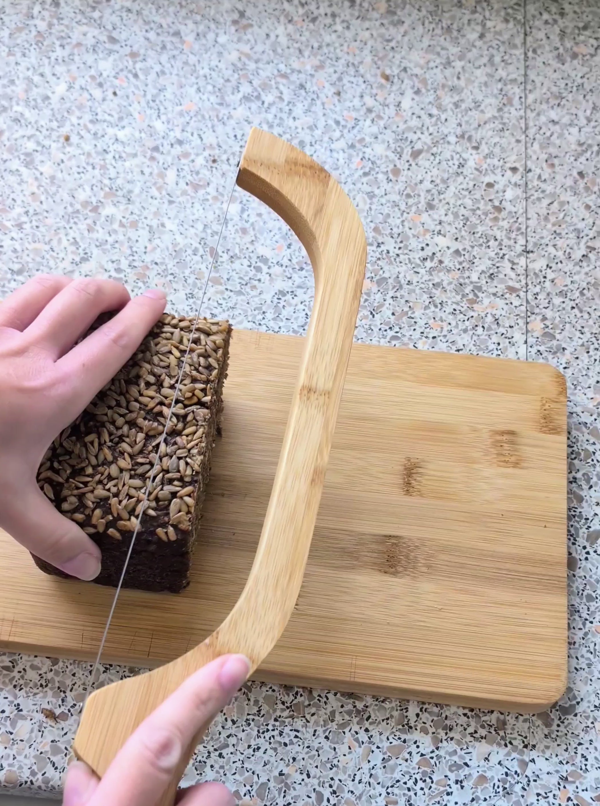 Video laden: Bambus-Schneidebrett mit integriertem Bogenmesser in Aktion. Präzises Schneiden von Vollkornbrot.
